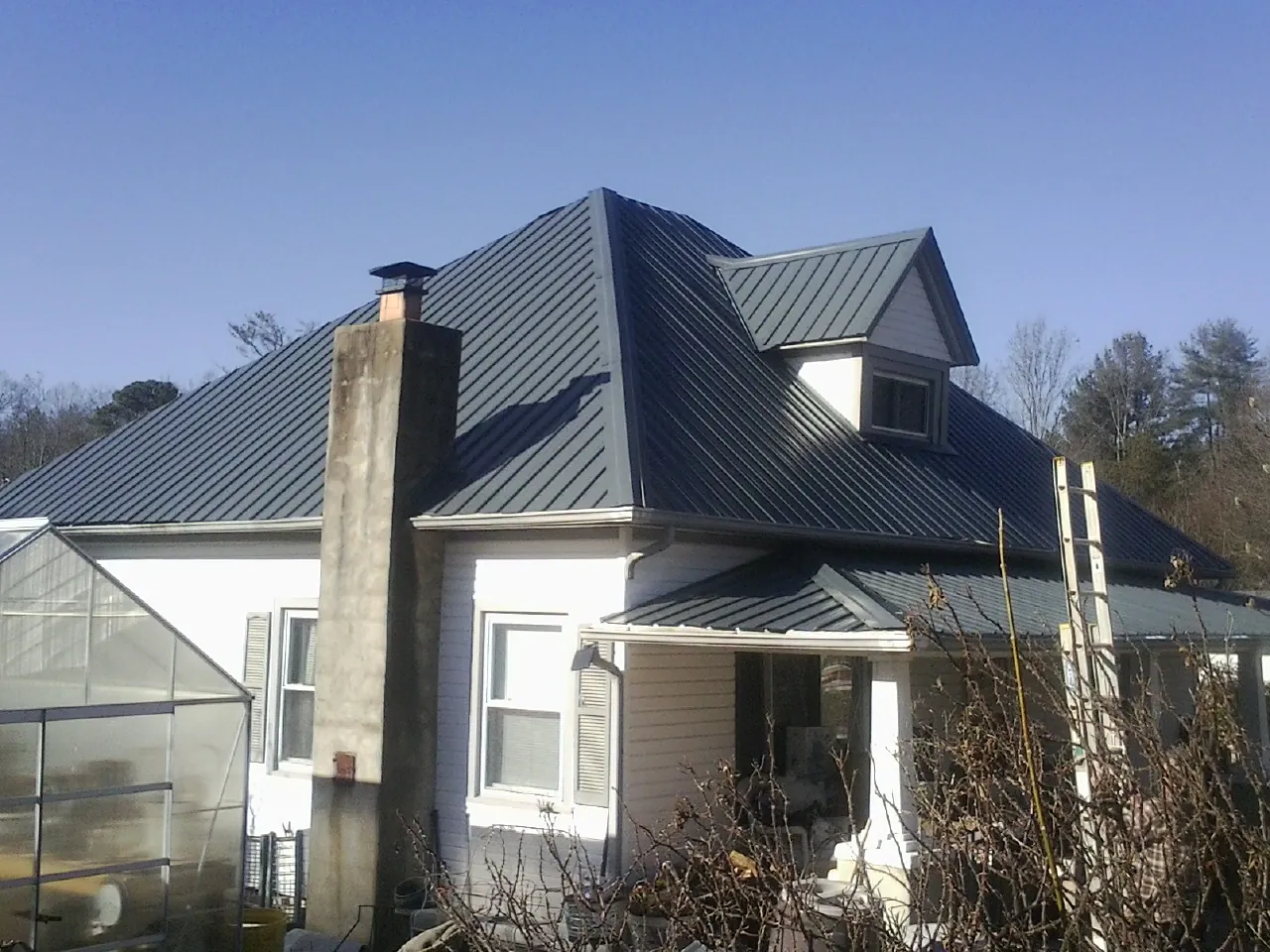 Dark blue standing seam metal roof on a white farmhouse with dormer — Slate & Tile Roof Repair by Roofing Brothers in White Oak