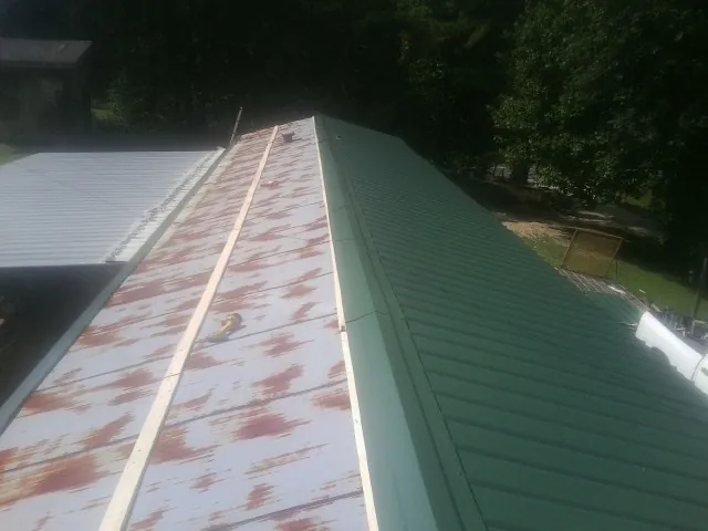 Old rusted panels beside newly installed green metal roofing — Wind Damage Roof Repair by Roofing Brothers in White Oak