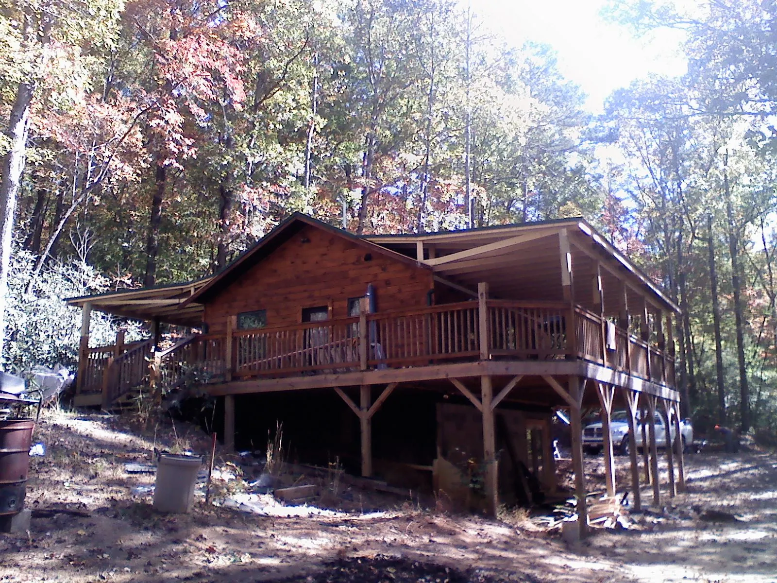 Log cabin with a wraparound porch and metal roof in the fall in White Oak