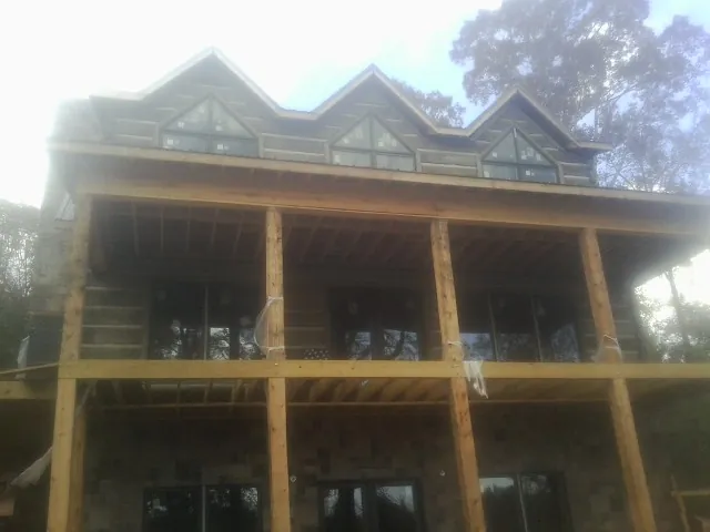 Dormers and porch framing on a large log home under construction — Roof Coating work by our crew in White Oak